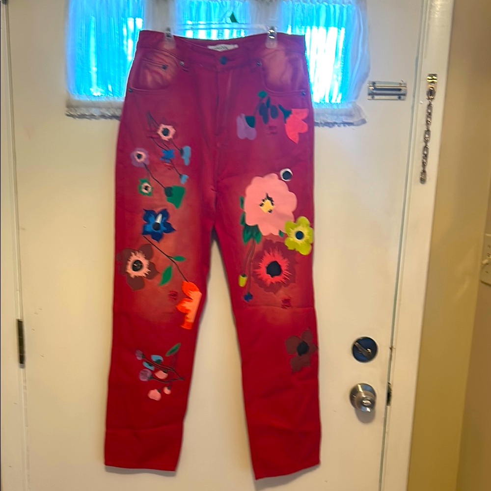 Women’s floral painted red jeans with light distressing.